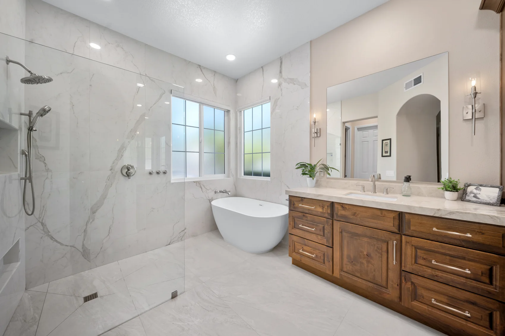 Bathroom remodel with marble-look walls, freestanding tub, and wood vanity