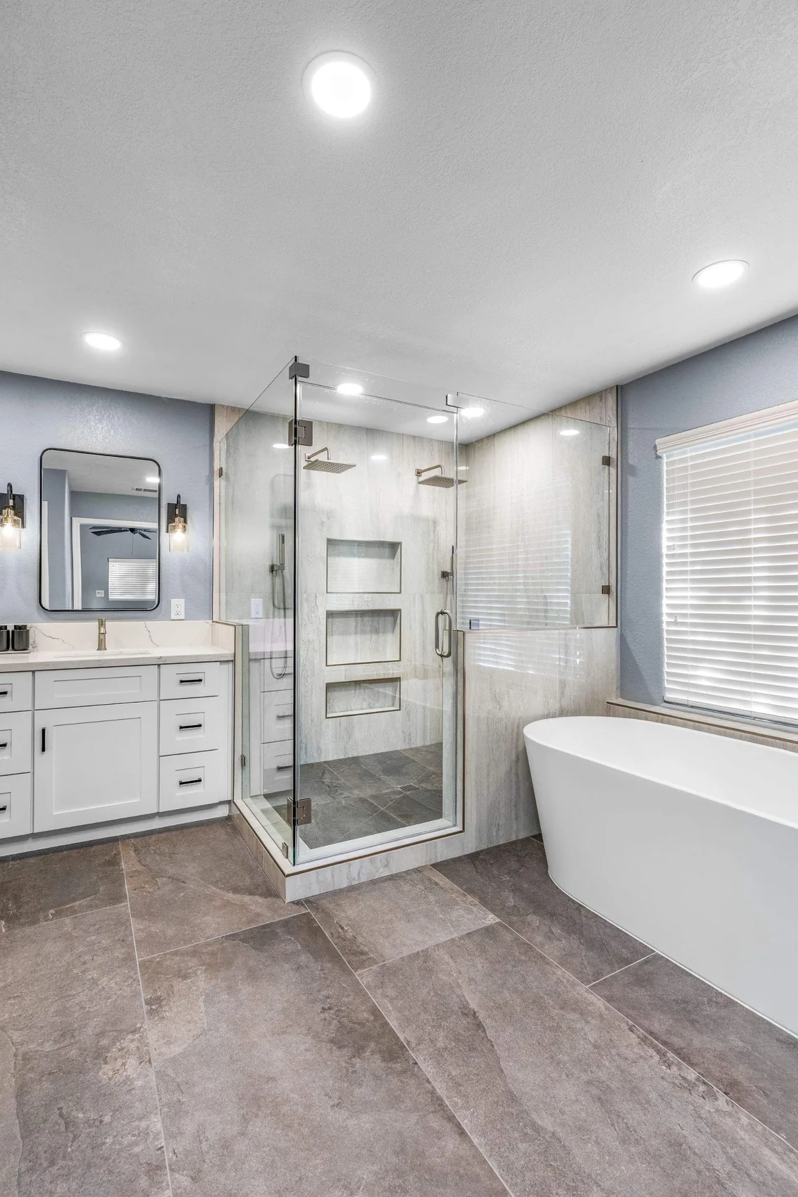 Bathroom remodel with a glass walk-in shower, white vanity, and freestanding tub