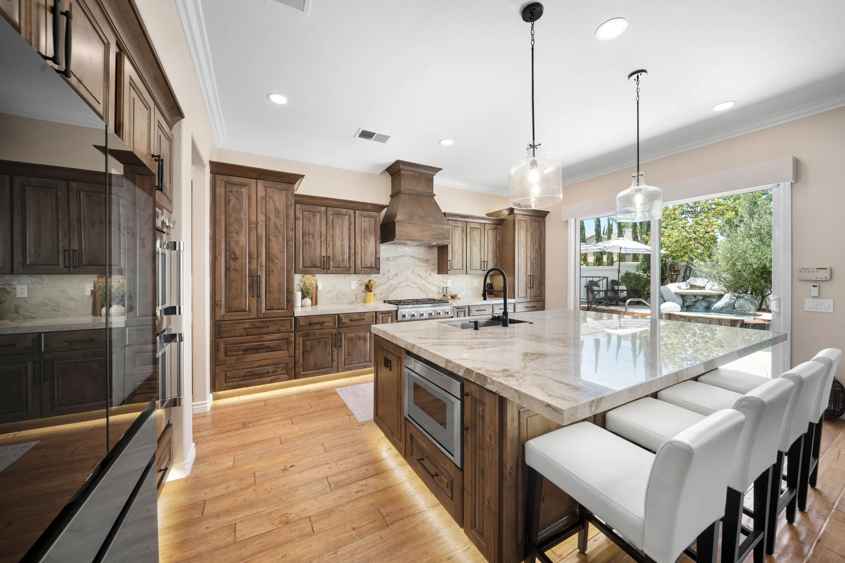 Kitchen remodel with wood cabinets, a large stone island, and white seating