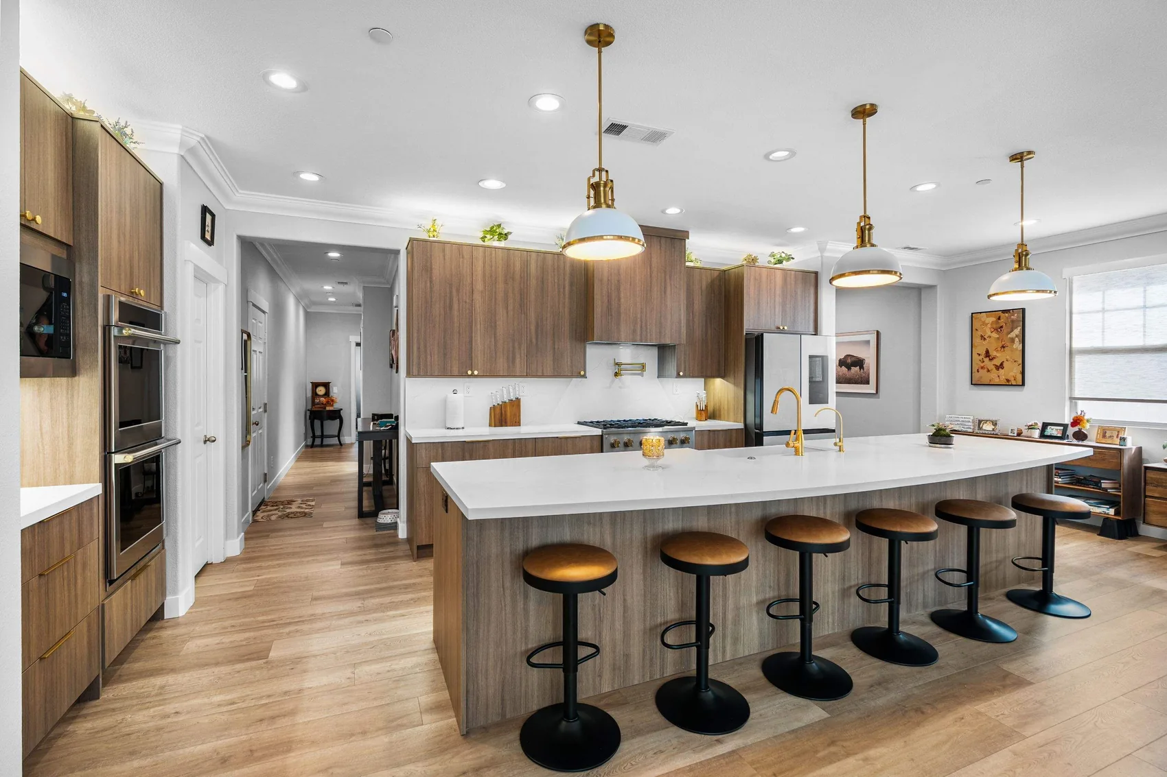 Kitchen remodel with walnut cabinets, white island, and gold pendant lights